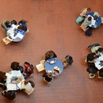 Schülerinnen und Schüler an runden Tischen im Lichthof der Kantonsschule Reussbühl